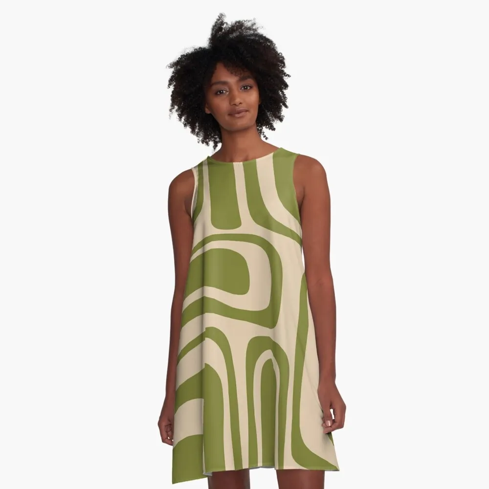 A woman is wearing a sleeveless, A-line dress with a bold green and beige abstract pattern.