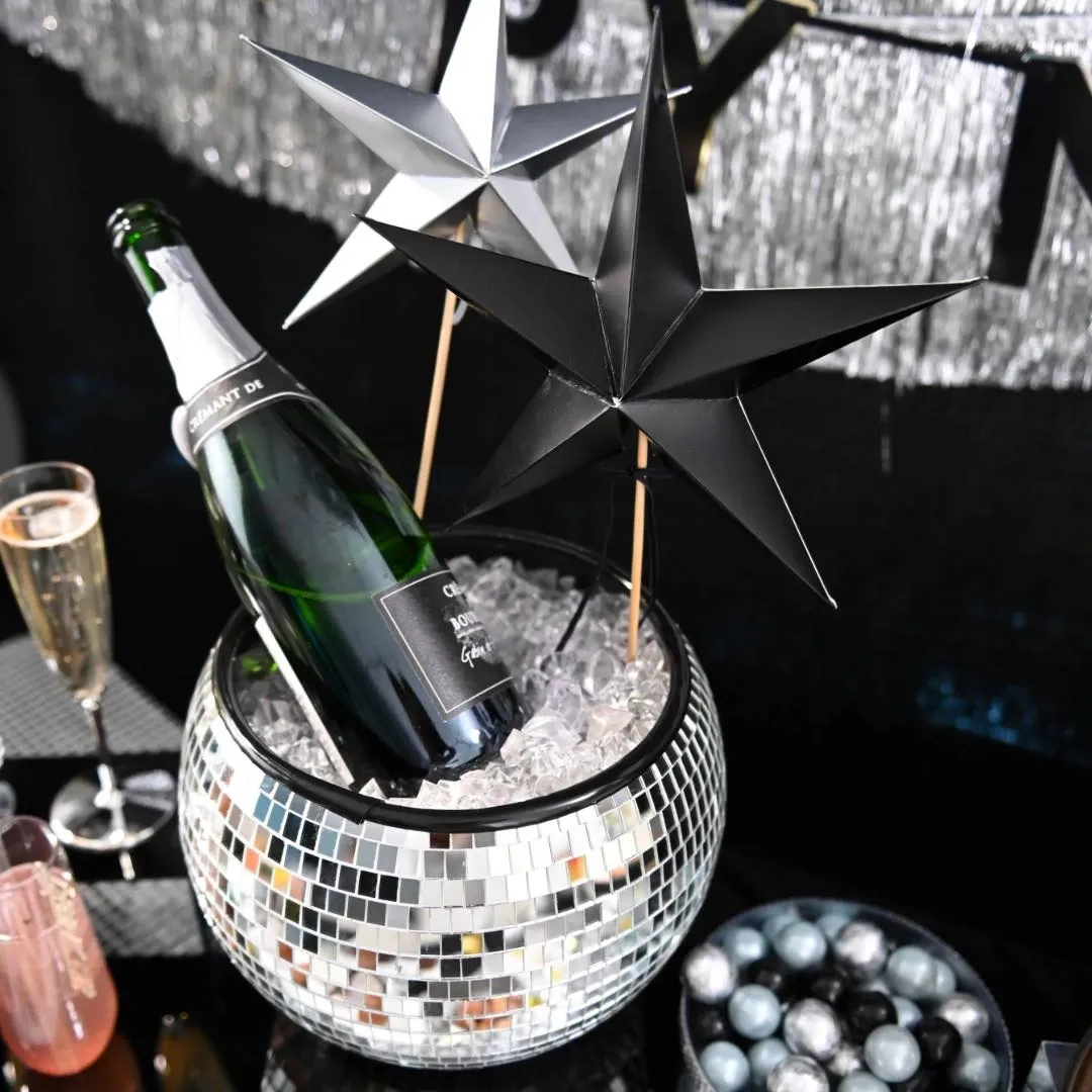 A shiny disco bucket filled with ice holds a champagne bottle and star decorations. (Image: Party City)
