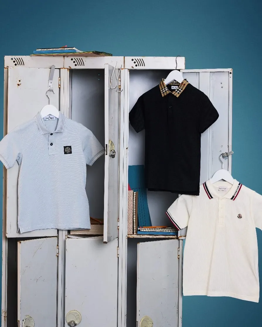 Three polo shirts for boys hang on while vintage lockers against a teal wall. (Image: FLANNELS)