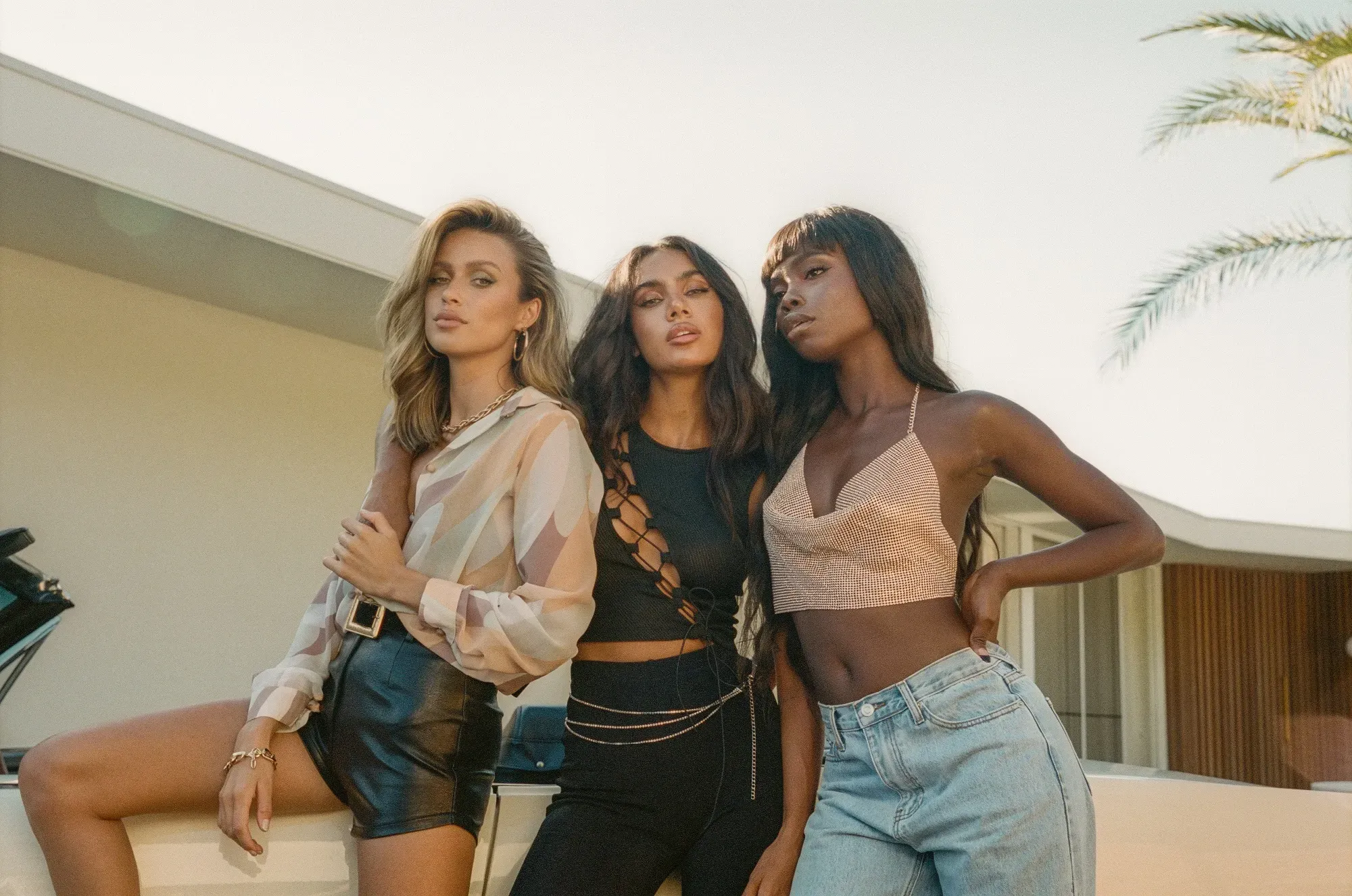 Three women are posing stylishly outdoors in trendy outfit. (Image: Emily Bencic)