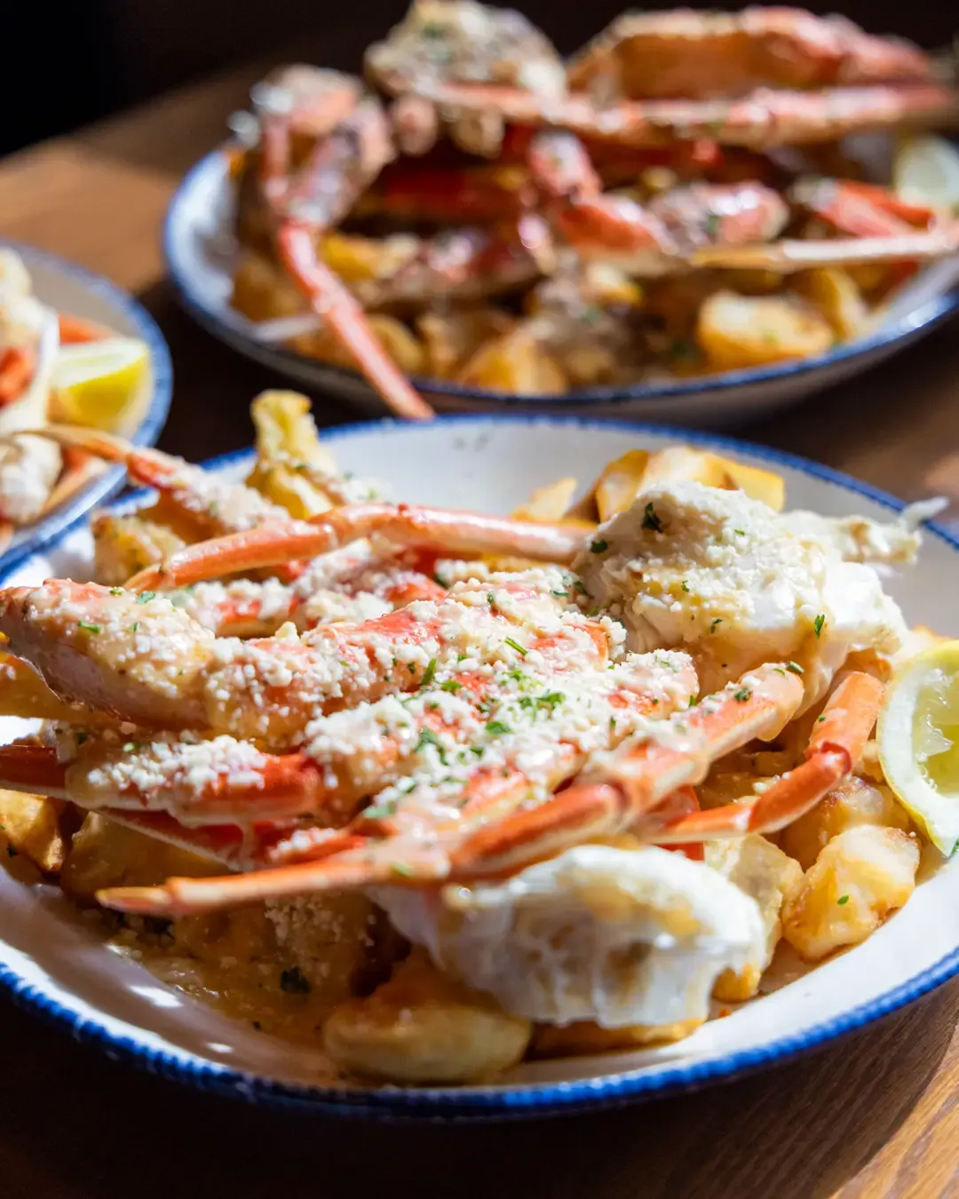 A plate of crab legs served with potatoes, lemon, and sprinkled cheese or herbs.