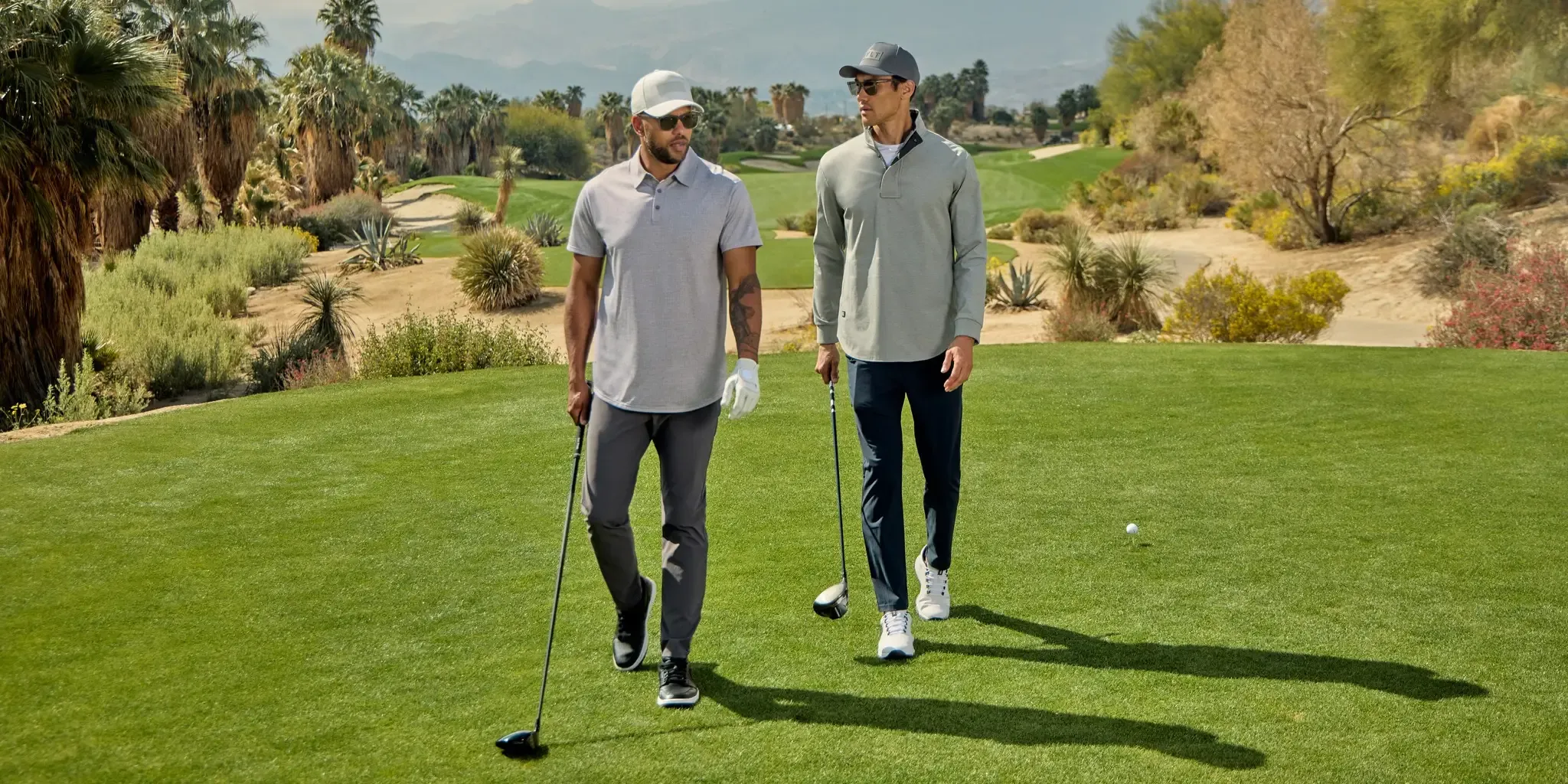 Two men wearing BYLT brand clothing walking on a golf course.