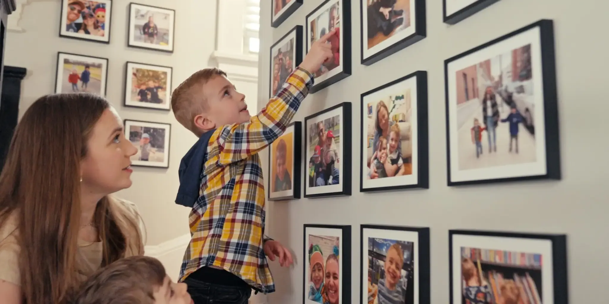 A boy pointing to a Mixtiles photo while his family watches.