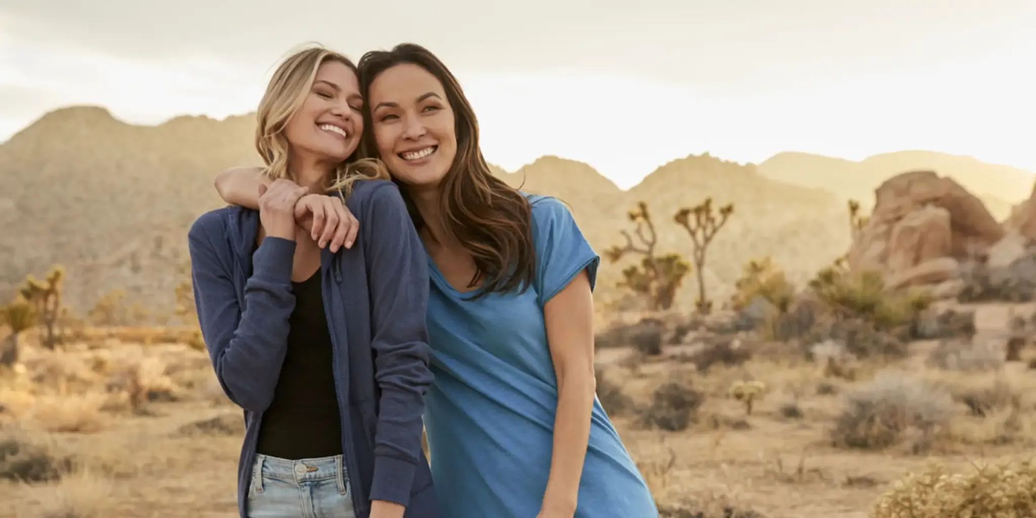Two smiling women in Pact clothing standing outside