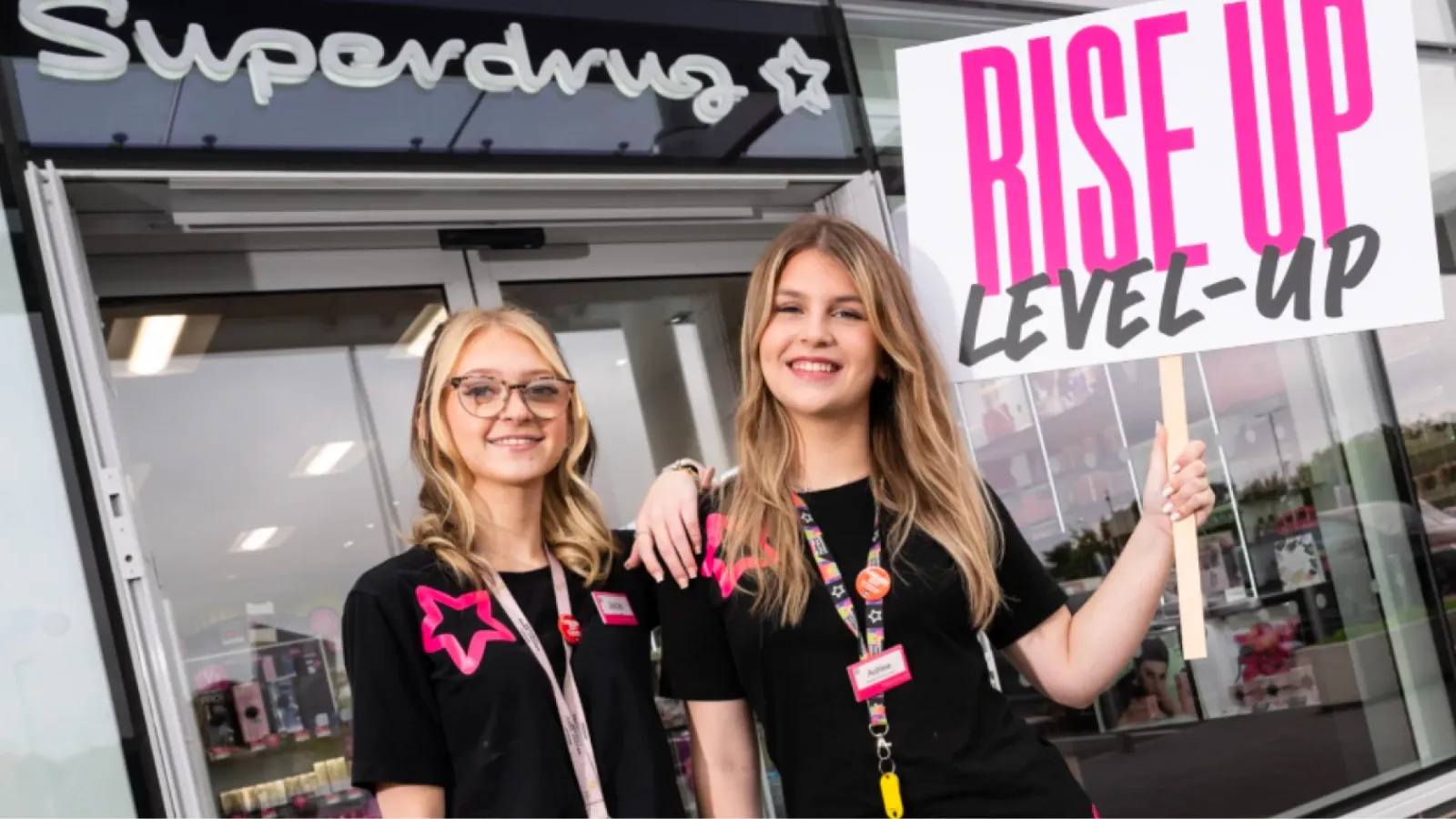 two Superdrug employees holding sign