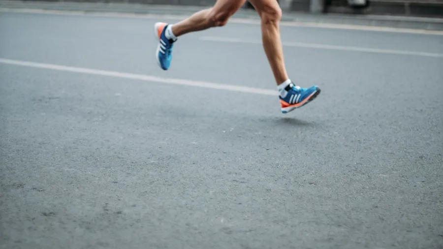 Close-up view of a runner's feet and lower legs during a running stride on pavement