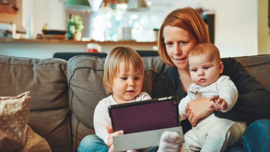 Family members using various devices connected to home internet in a modern living room