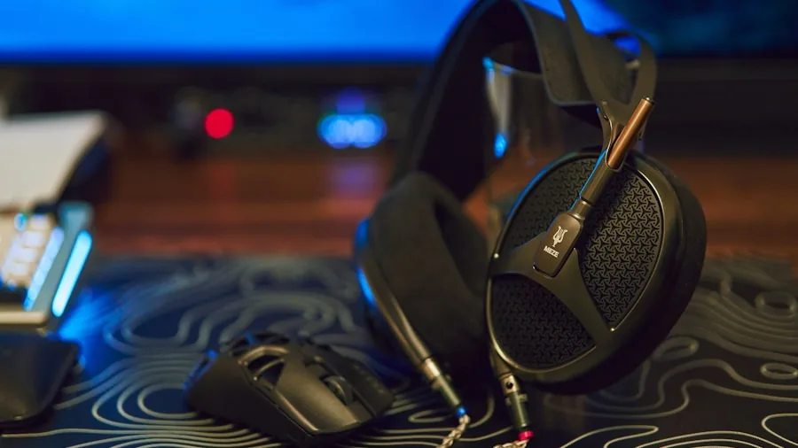 Gamer wearing wired headset at desktop computer setup in home gaming room