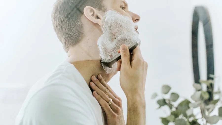 Man shaving face in bathroom mirror during morning grooming routine