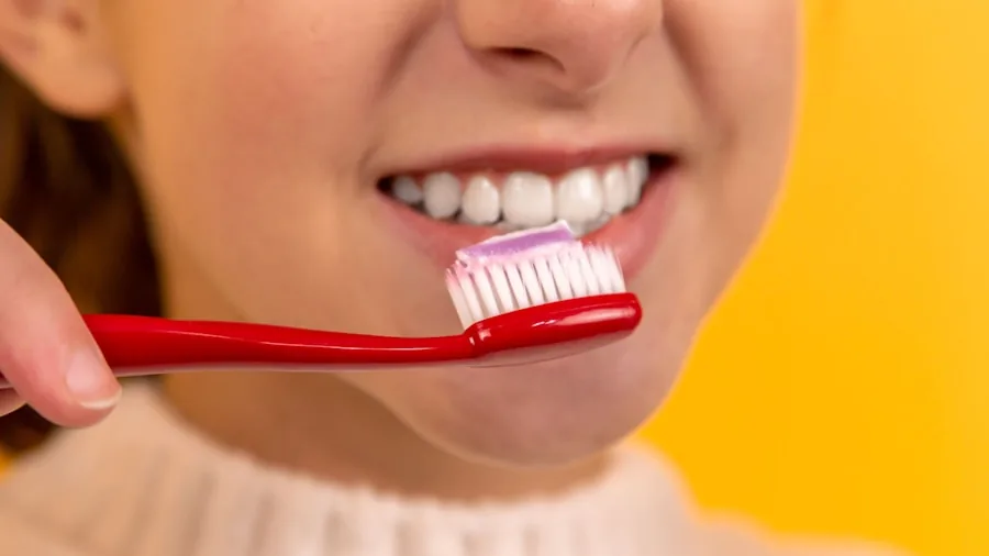 Person brushing teeth at bathroom sink during morning dental care routine