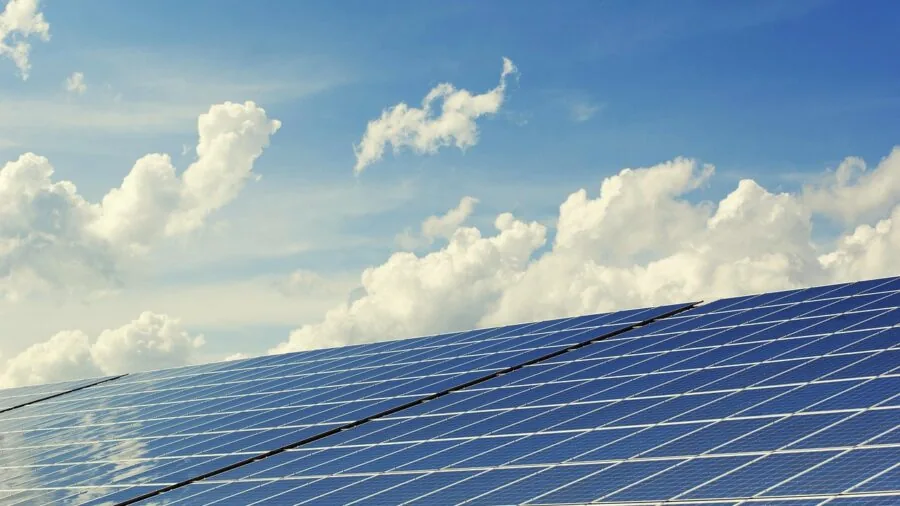 Person charging devices outdoors using solar panels during camping adventure in natural sunlight