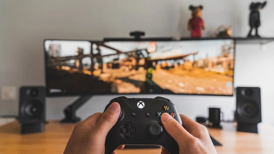 Person deeply engaged in competitive gaming with curved monitor setup in home gaming environment