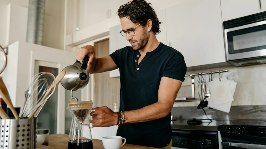 Person grinding fresh coffee beans in kitchen with espresso setup and natural morning light