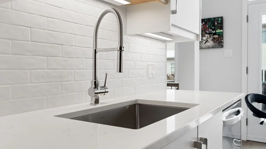 Person installing kitchen plumbing fixtures under a modern sink with tools and pipes visible