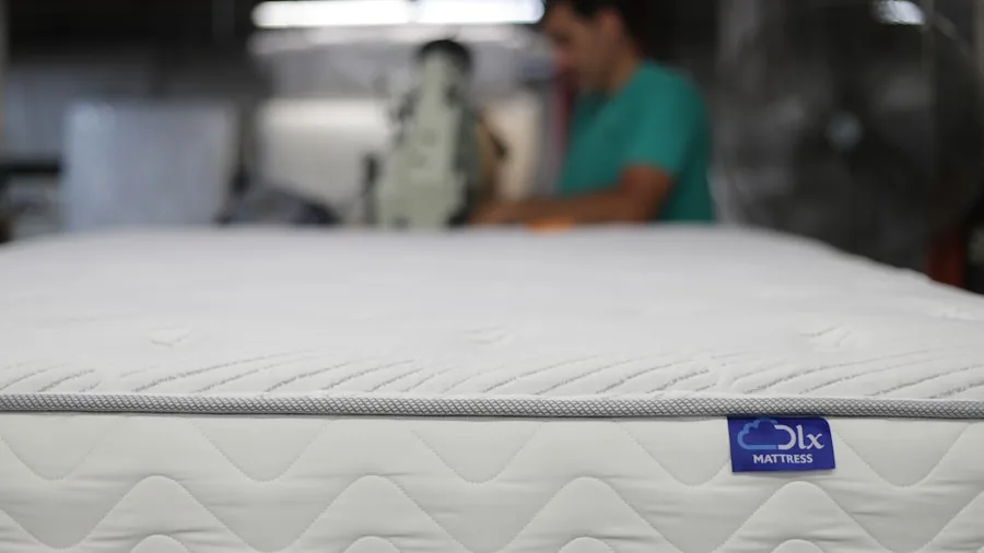 Person measuring mattress height and thickness while checking bed frame compatibility in bedroom