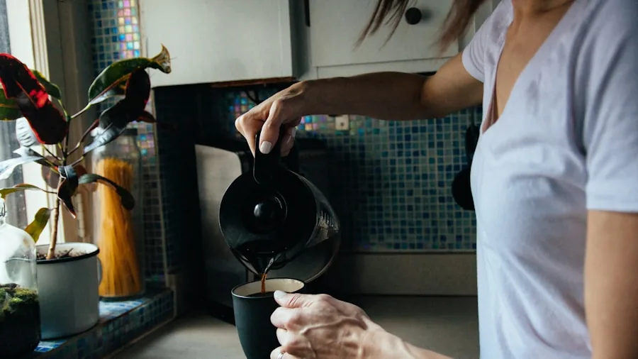 Person pouring fresh brewed coffee into glass carafe in bright kitchen during morning routine