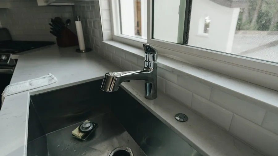 Person rinsing dishes at kitchen sink, demonstrating water conservation and sustainable household practices