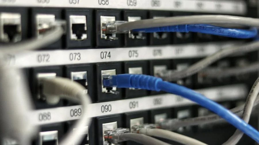 Person setting up home networking equipment with ethernet cables connected to router and devices