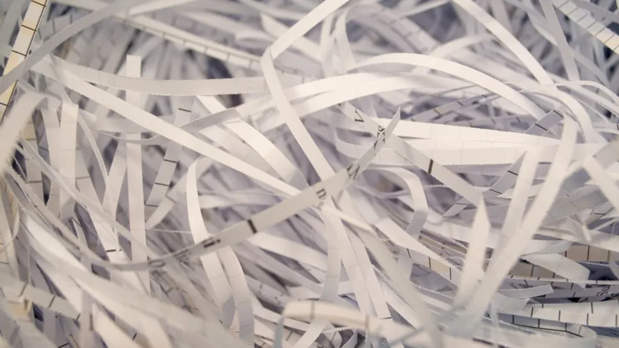 Person shredding sensitive documents into small pieces for data protection and privacy