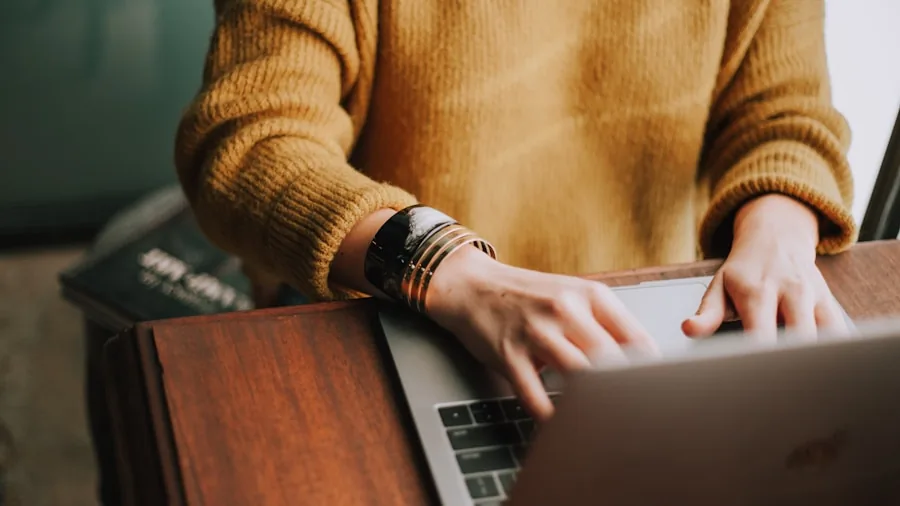 Person typing on laptop at desk while working on files and documents