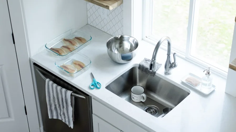Person washing dishes in a bright kitchen sink with soapy water and a sponge