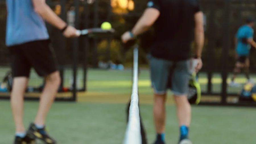 Two people enjoying a recreational pickleball game on an outdoor court on a sunny day